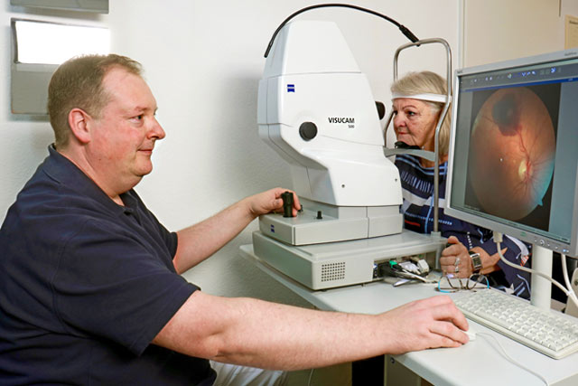 Ein Mitarbeiter fotografiert bei einer Patientin eine Netzhautveränderung